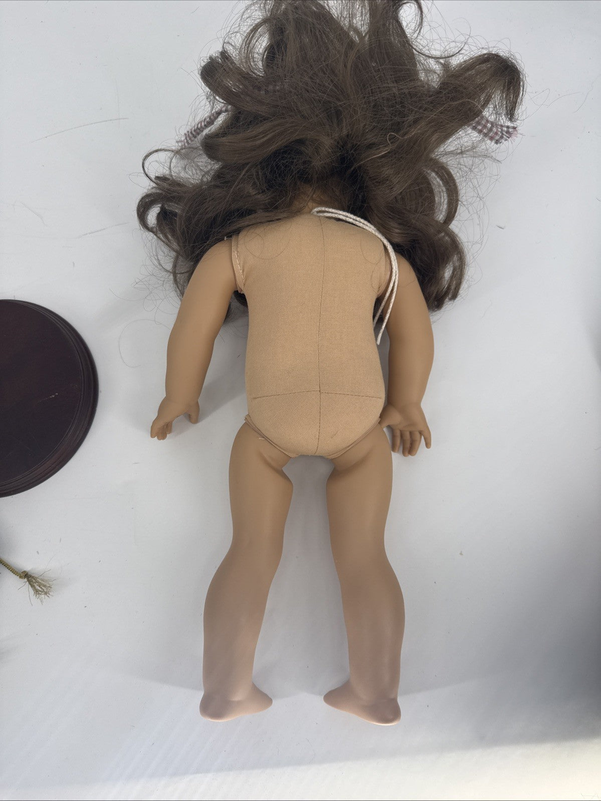 Naked doll with long brown hair on a white background