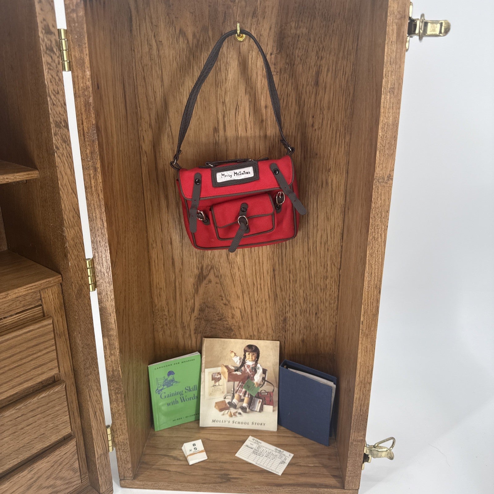 Red handbag hanging on a wooden cabinet with books and a box below