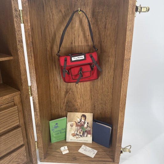Red handbag hanging on a wooden cabinet with books and a box below
