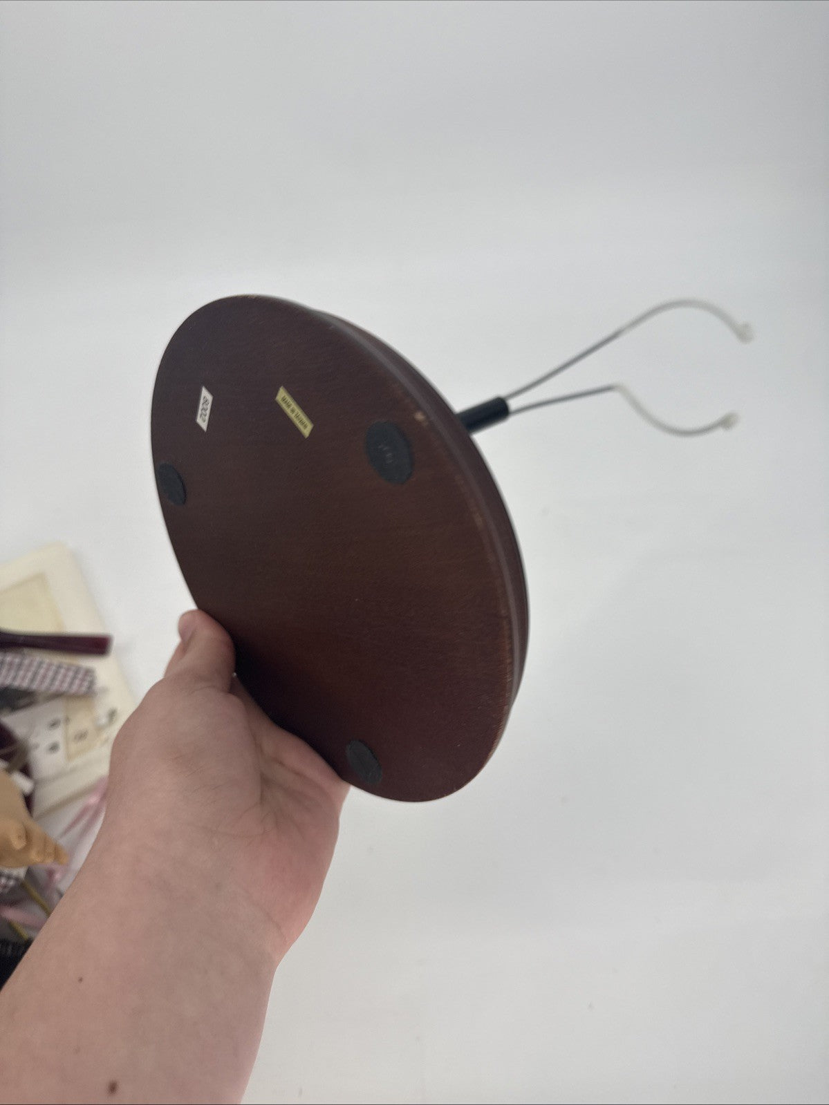 Hand holding a brown circular object with a white background