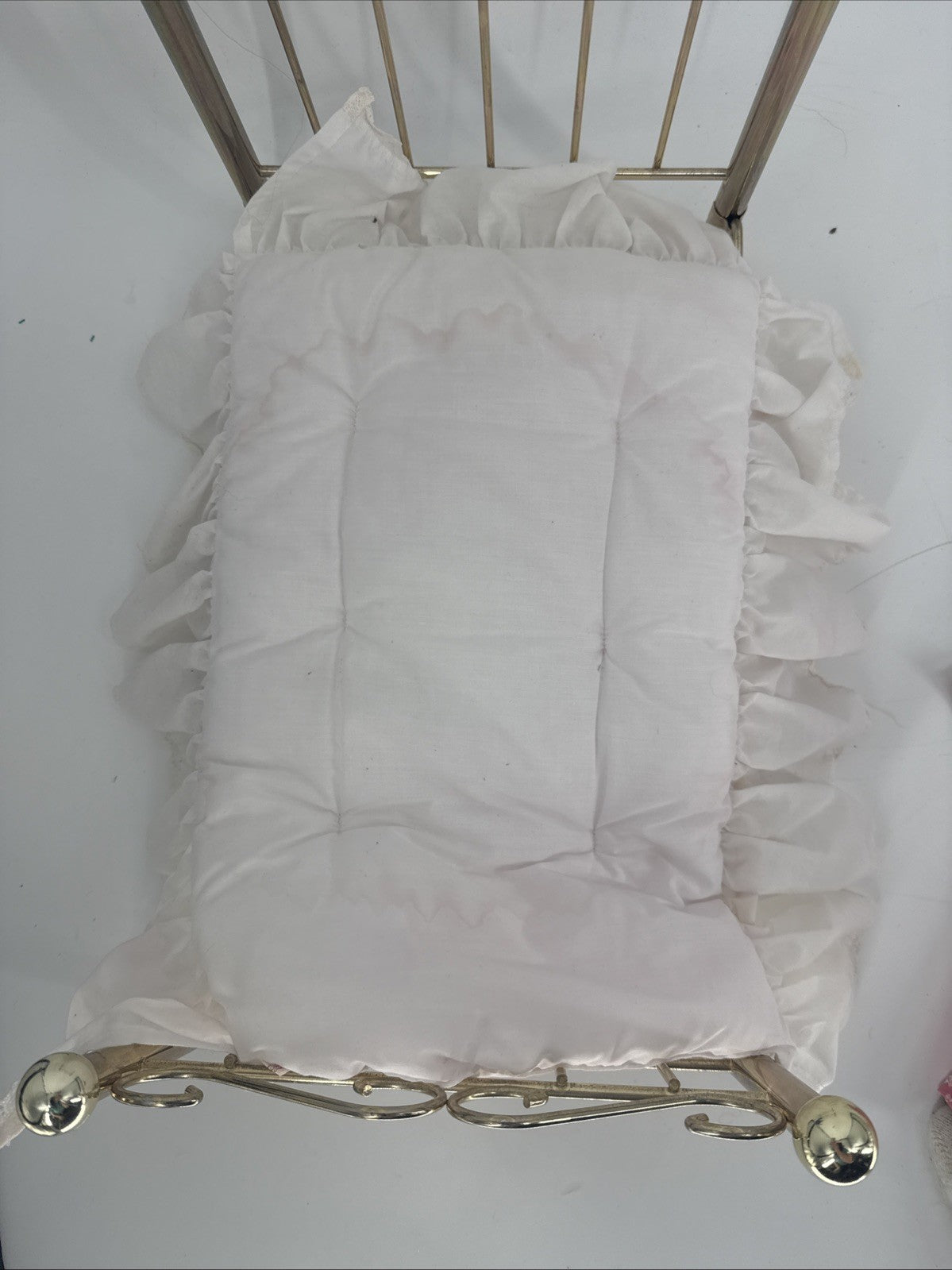 White ruffled pillow on a decorative metal stand against a white background