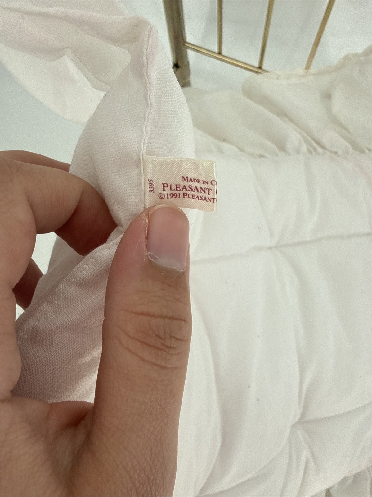 Hand holding a tag on a white garment with 'Pleasant' branding.