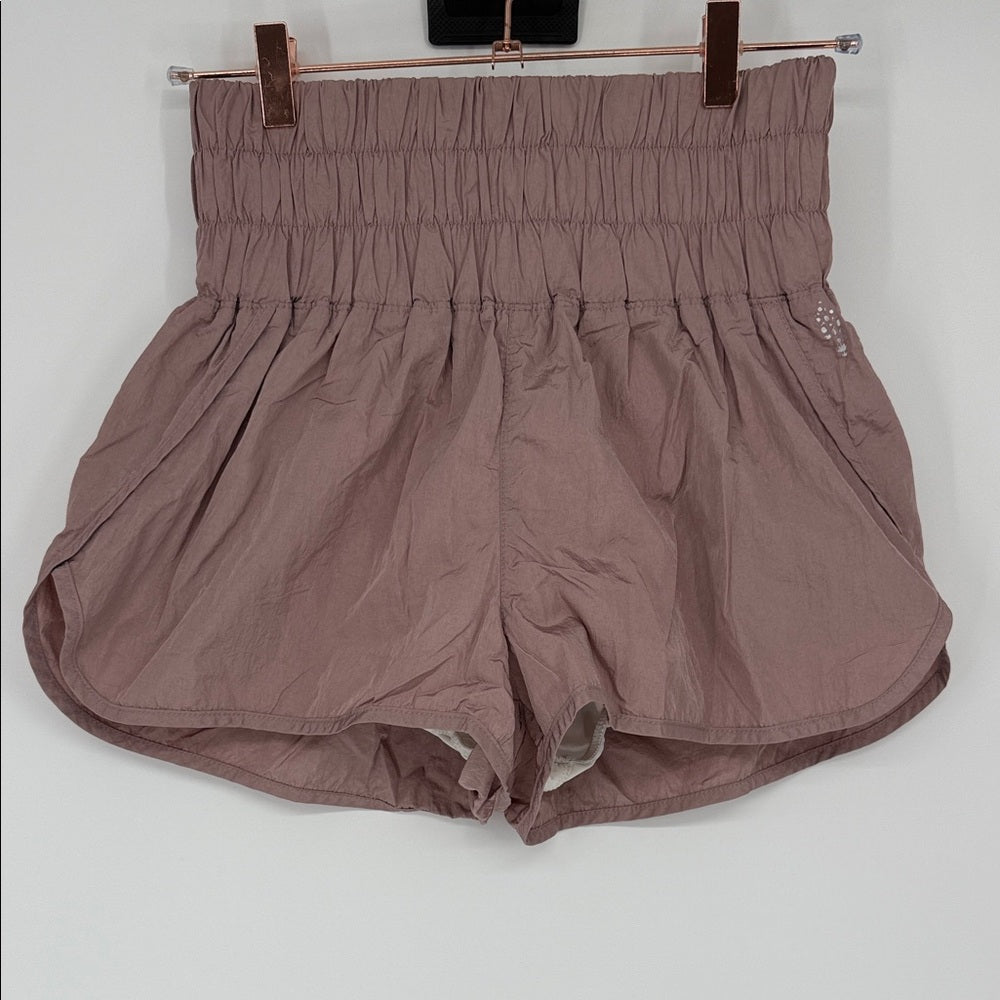 Brown shorts hanging on a rack against a white background