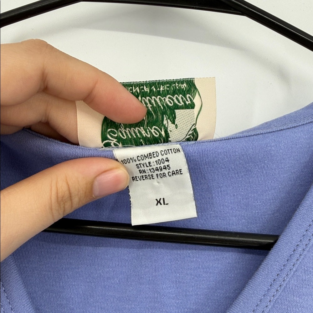 Hand holding a clothing tag on a blue garment with visible brand name.