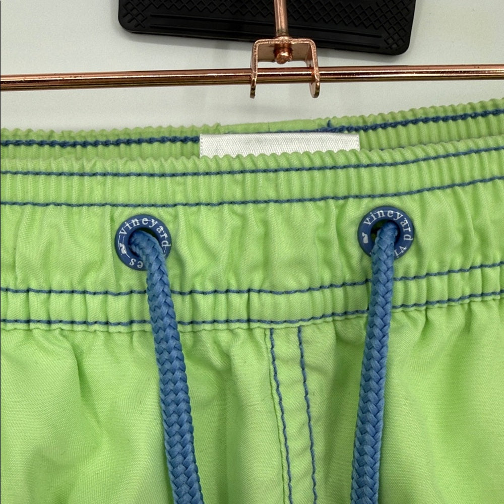 Green swim shorts with blue drawstrings on a hanger