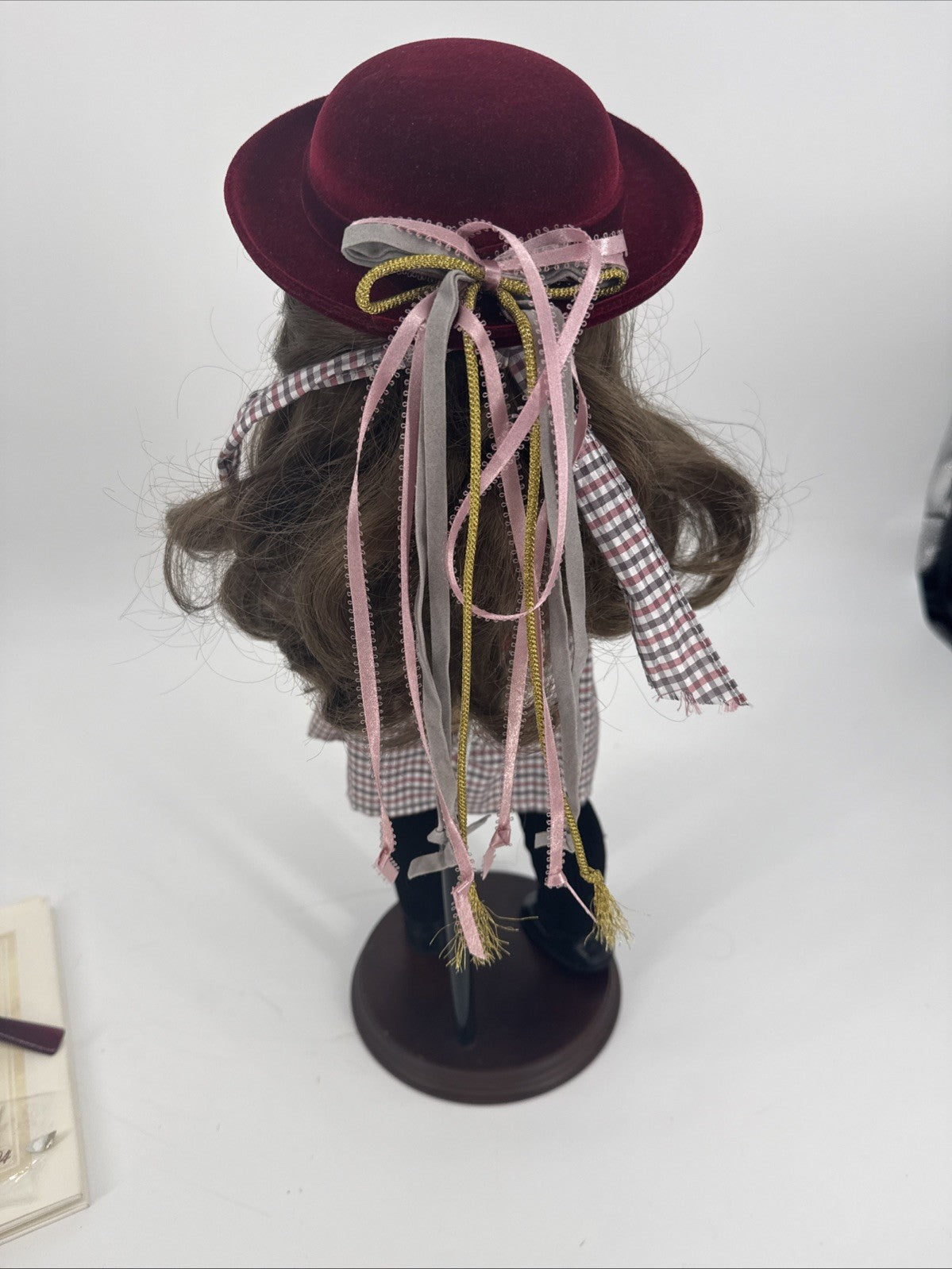 Doll with a burgundy hat and colorful ribbons on a white background