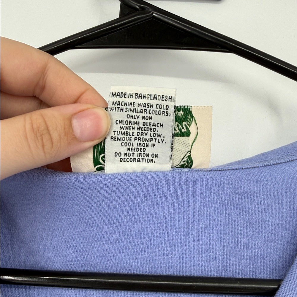 Clothing label on a blue garment with a hand holding it