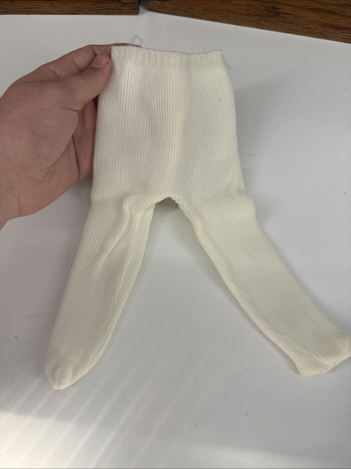 White baby tights held by a hand on a white background