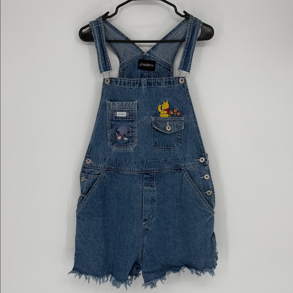 Blue denim overall dress with embroidered designs on a white background