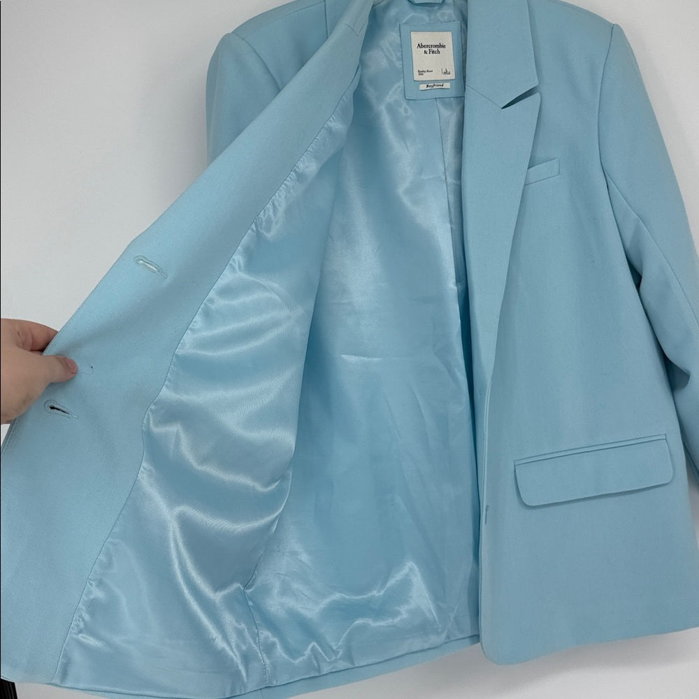 Light blue blazer with a visible brand tag on a white background