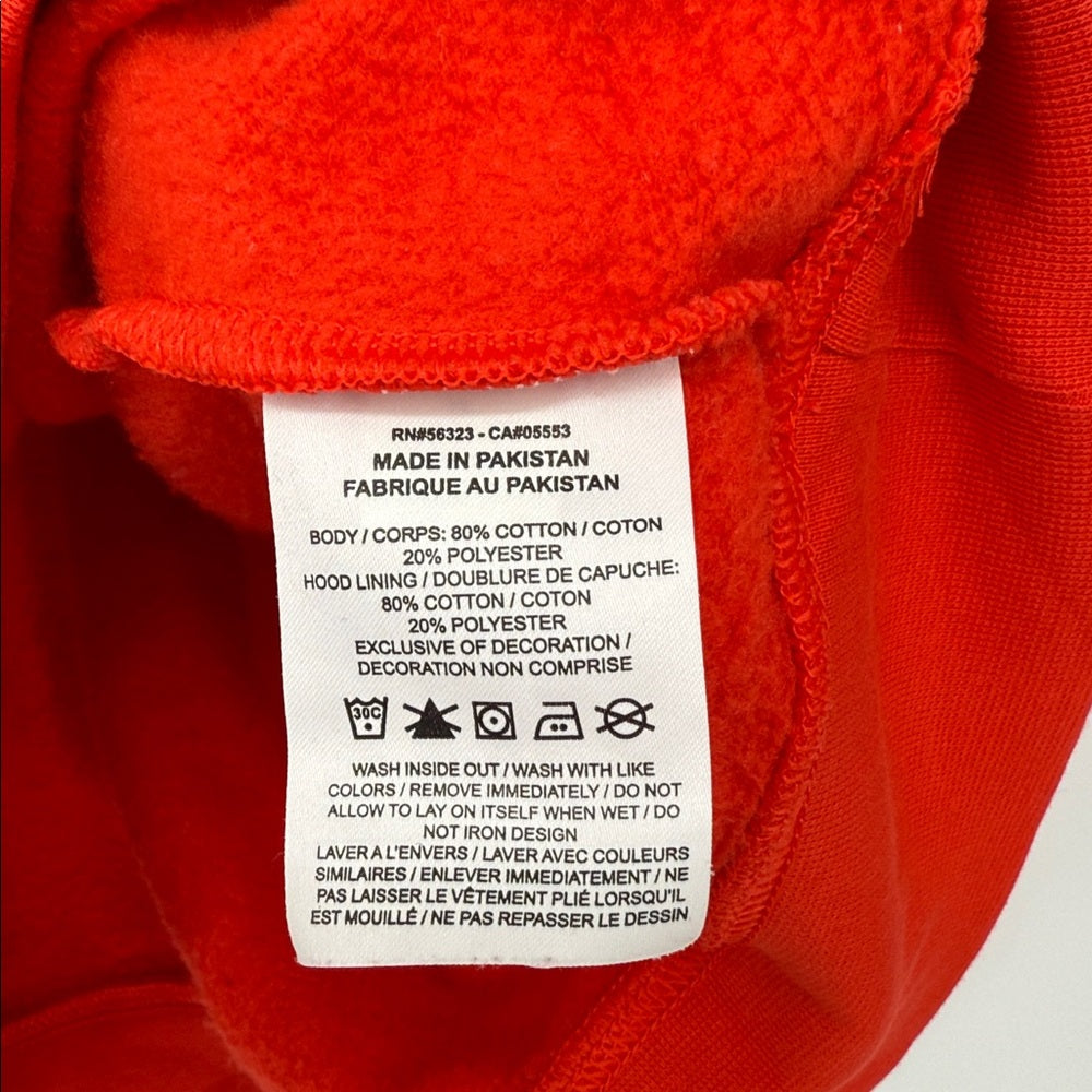 Red fleece garment with a label detailing fabric composition and care instructions.