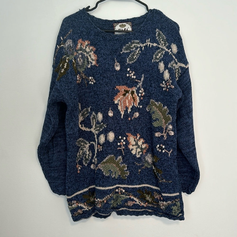 Blue knit sweater with an allover floral and botanical pattern, long sleeves, and ribbed hem.