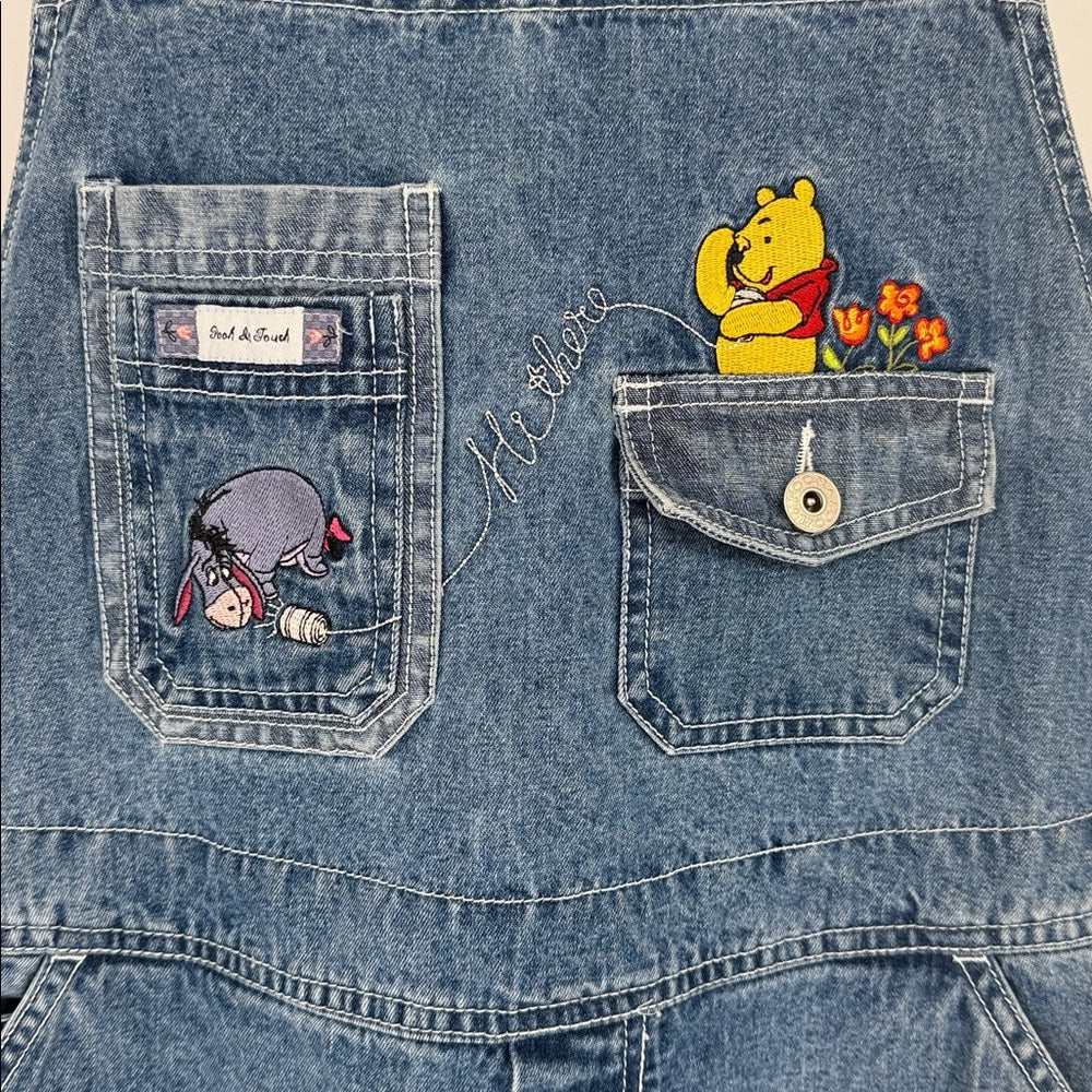 Denim jacket with embroidered patches of a bear and flowers, and a small creature.