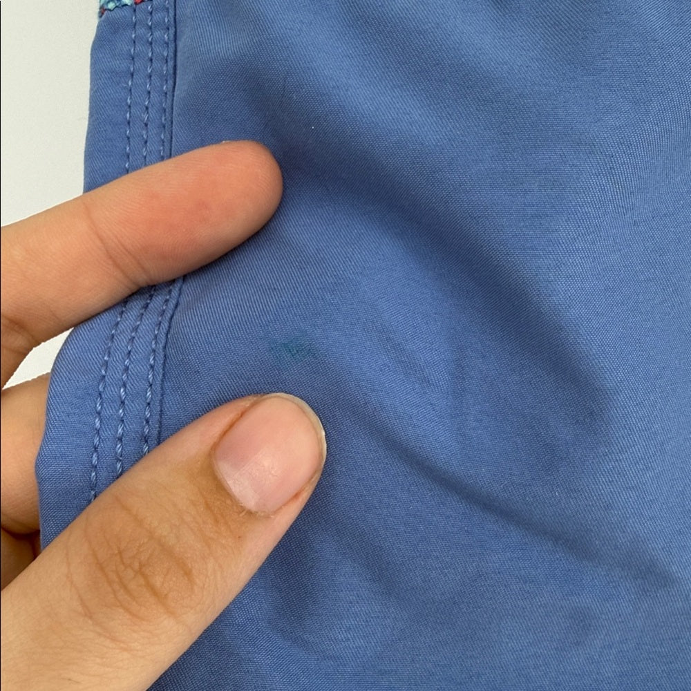Close-up of a hand holding blue fabric with stitching details.