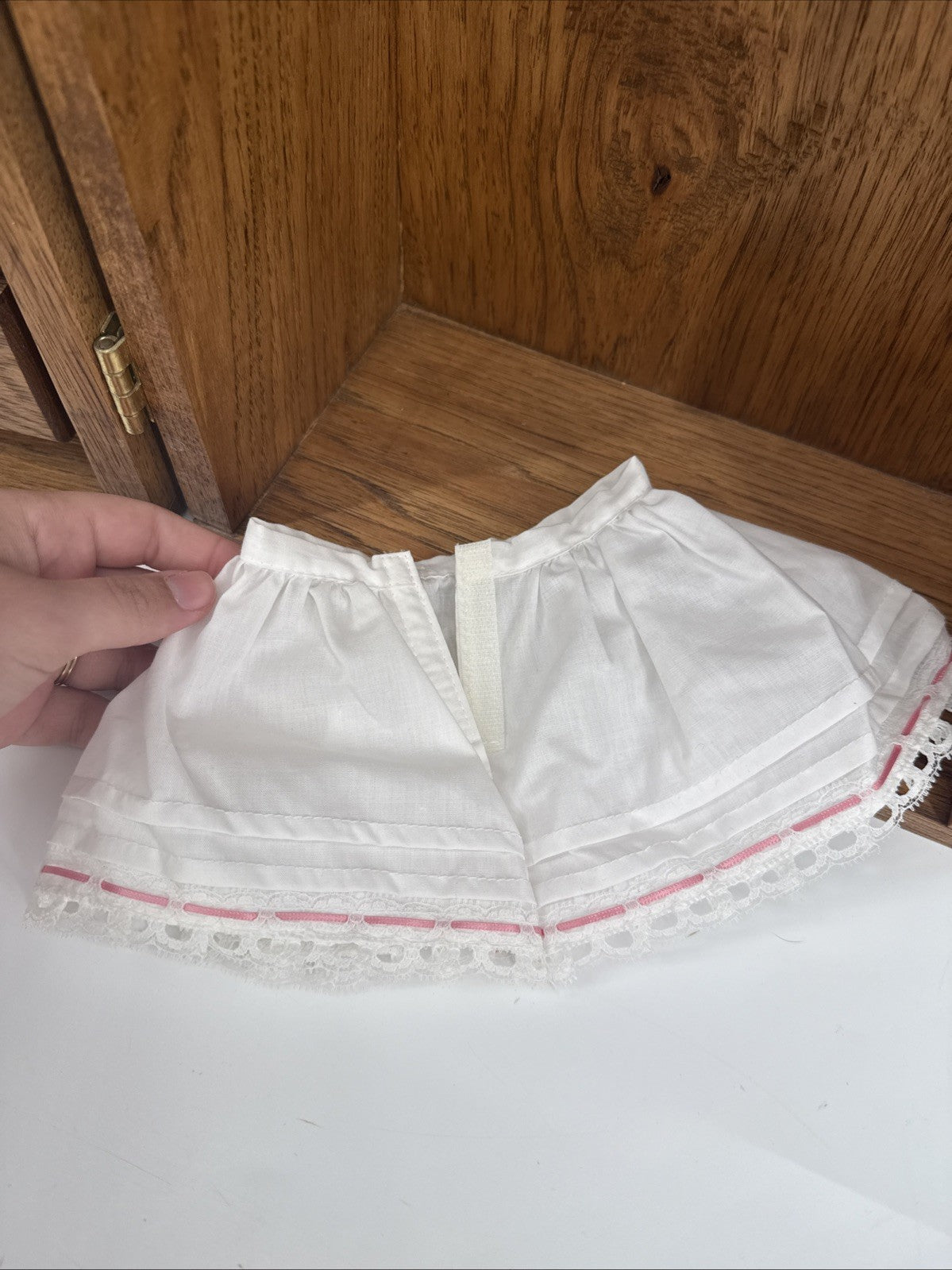 White lace collar on a white shirt with a wooden cabinet in the background