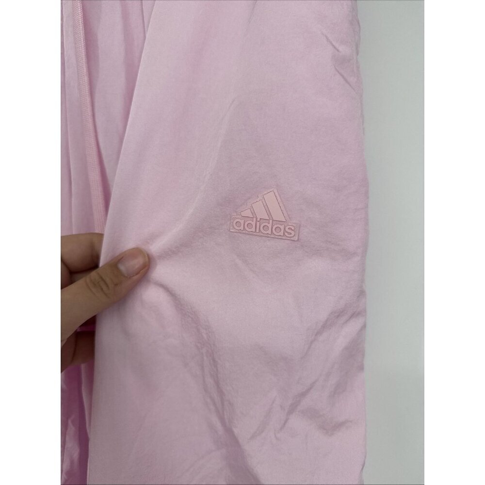 Pink Adidas garment held by a hand against a light gray background