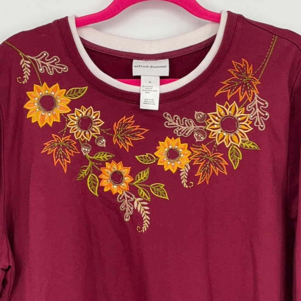 Maroon shirt with floral embroidery on a hanger
