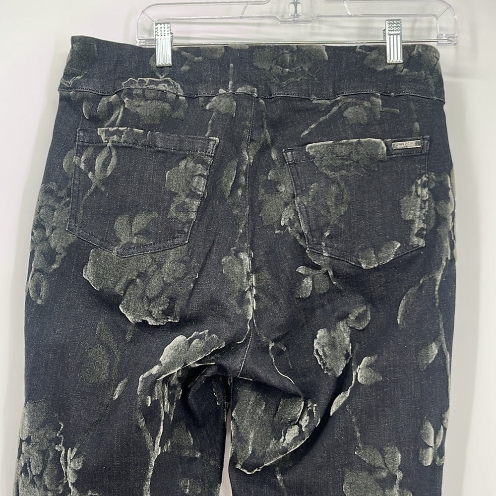 Black floral patterned pants on a hanger against a white background
