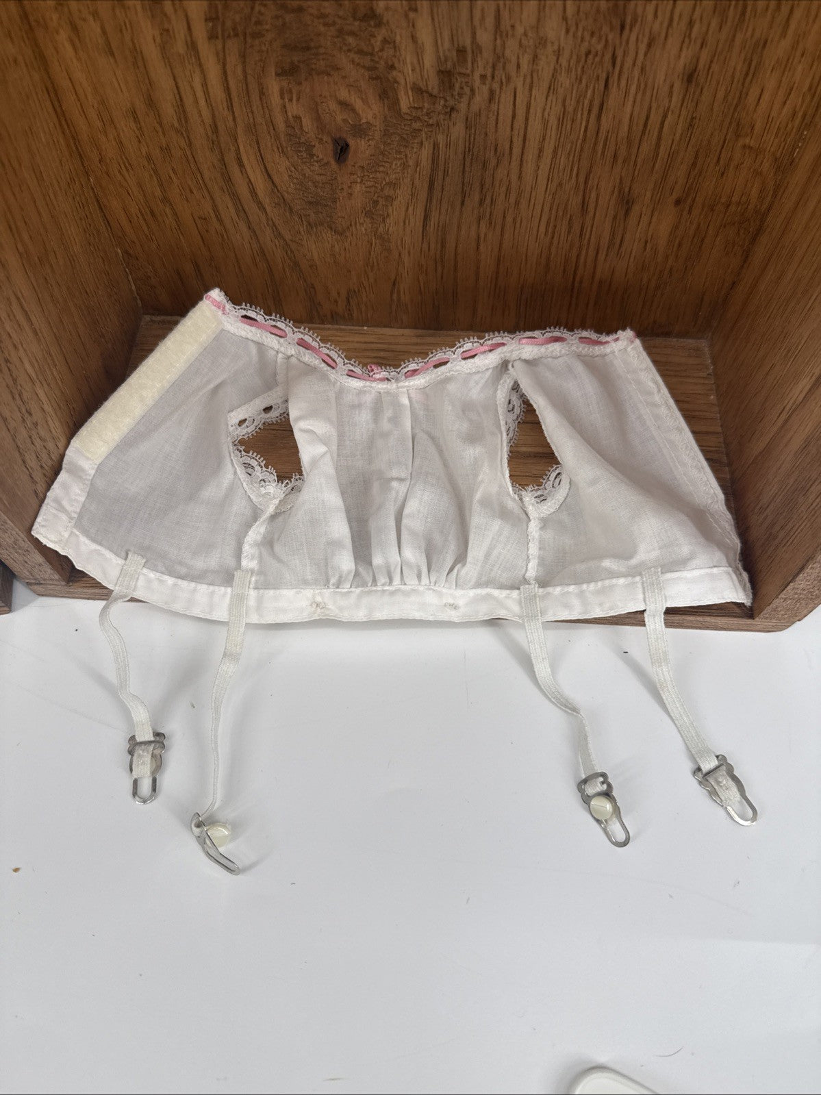White lace corset with suspenders on a wooden surface